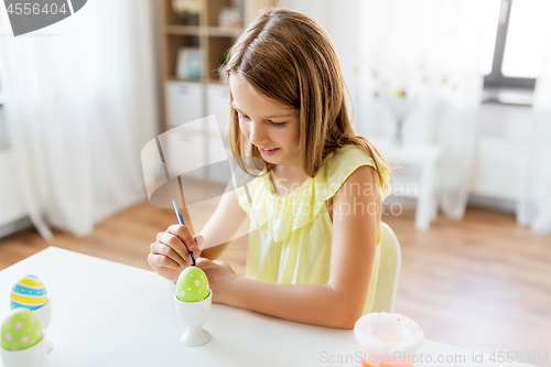 Image of happy girl coloring easter eggs at home