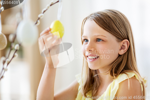 Image of girl decorating willow by easter eggs at home