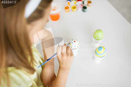 Image of close up of girl coloring easter egg by paintbrush