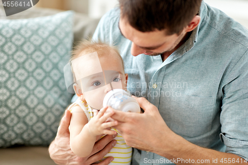 Image of father and baby drinking from bottle at home