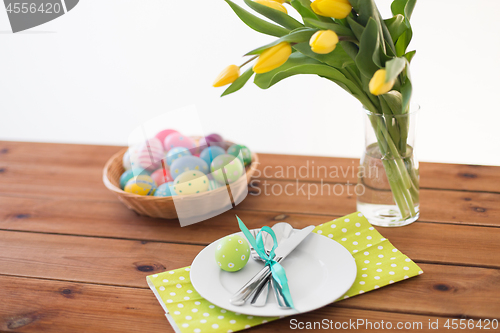 Image of easter eggs in basket, plates, cutlery and flowers