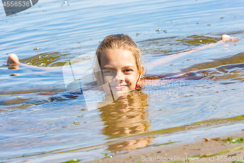 Image of A ten-year-old girl lies in the water near the river