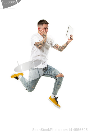 Image of Image of young man over white background using laptop computer while jumping.