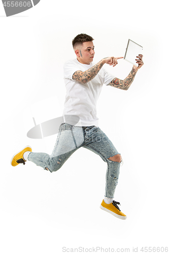 Image of Image of young man over white background using laptop computer while jumping.