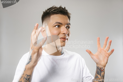 Image of The young attractive man looking suprised isolated on gray