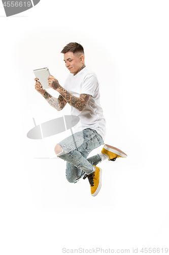 Image of Image of young man over white background using laptop computer while jumping.