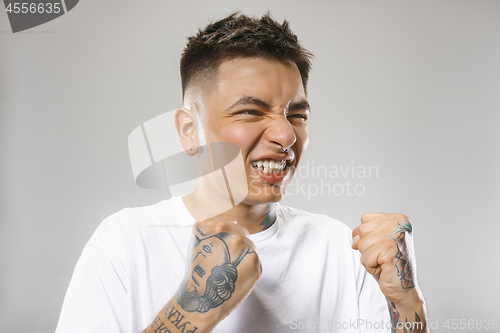 Image of The young emotional angry man screaming on gray studio background