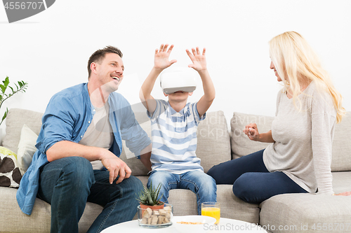 Image of Happy family at home on living room sofa having fun playing games using virtual reality headset