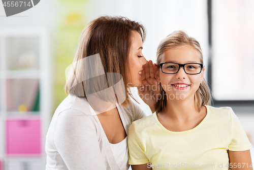 Image of happy mother whispering secret to daughter at home
