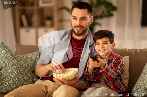 Image of father and son with popcorn watching tv at home