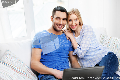 Image of happy couple with laptop computer at home