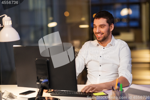 Image of happy businessman with computer at night office