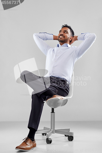 Image of smiling indian businessman sitting on office chair