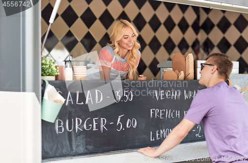 Image of saleswoman at food truck serving male customer