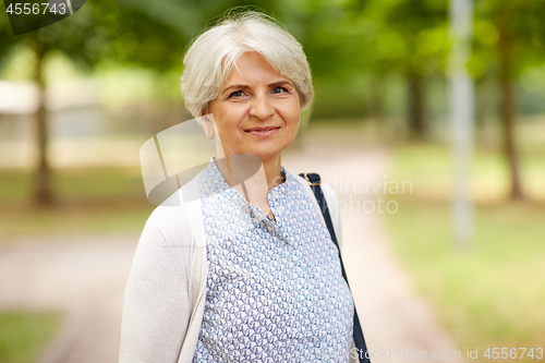 Image of portrait of happy senior woman at summer park