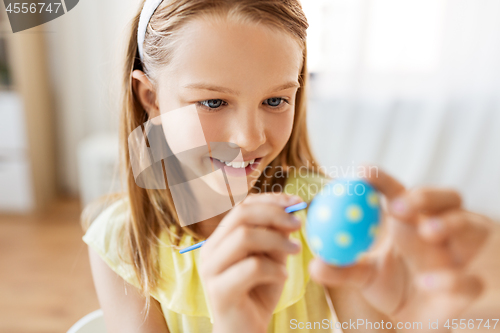 Image of happy girl coloring easter egg at home