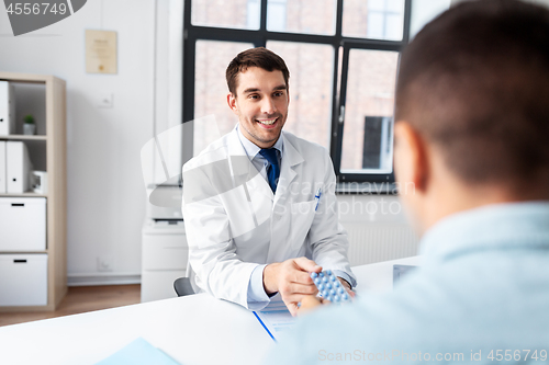 Image of doctor giving medicine to male patient at hospital