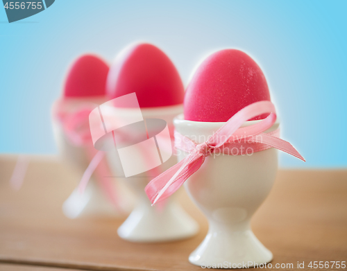 Image of pink colored easter eggs in holders on table