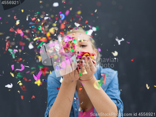 Image of woman blowing confetti in the air isolated over gray