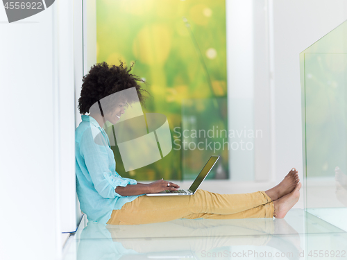 Image of black women using laptop computer on the floor