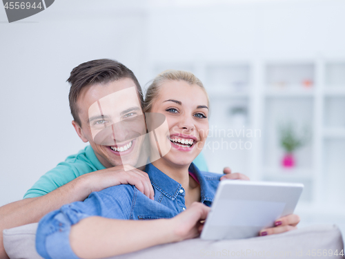 Image of couple relaxing at  home with tablet computers