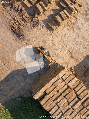 Image of The loader stacks bales of straw into the stack after harvesting the grain. Top view.