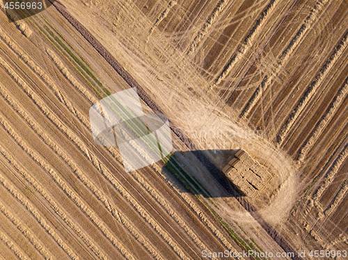 Image of Top view from flying drones to an agricultural field after harvesting with a stacks of straw on it at summer day.