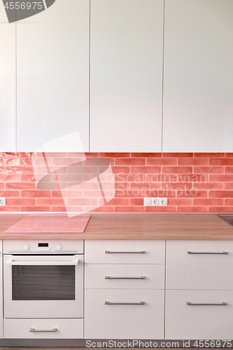 Image of Kitchen facades with modern built-in kitchen appliances. Materials tiles in a trend color of the year 2019 Living Coral Pantone.