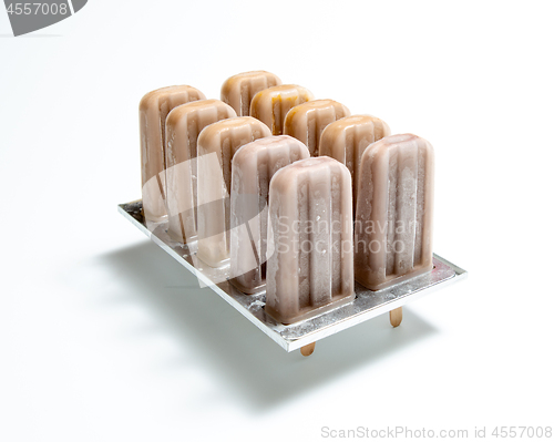 Image of Coffee ice cream. Plastic molds with homemade ice cream on a sti