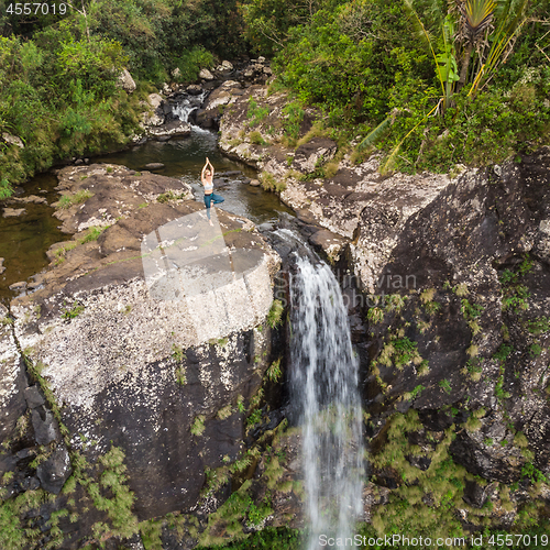 Image of Active sporty woman relaxing in nature, practicing yoga on high clif by 500 feet waterfall at Black river gorges national park on tropical paradise island of Mauritius