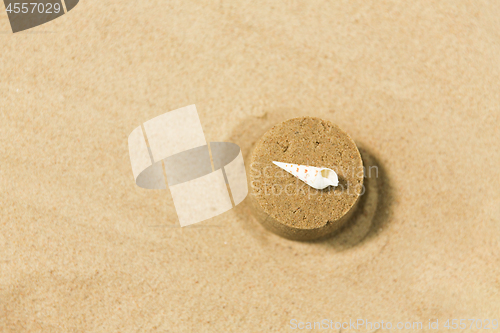 Image of sand shape made by mold with shell on summer beach