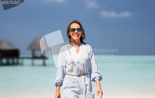 Image of happy woman over tropical beach and bungalow