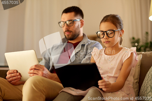 Image of father and daughter with tablet computers at home