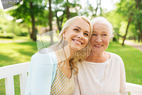 Image of daughter with senior mother sitting on park bench