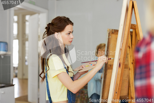 Image of woman with easel painting at art school studio