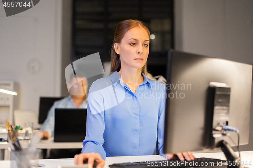 Image of businesswoman at computer working at night office