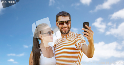 Image of happy couple taking selfie by smartphone in summer