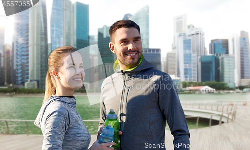 Image of couple with bottles of water over singapore city