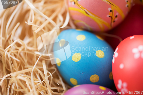 Image of close up of colored easter eggs in straw