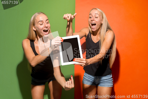 Image of Portrait of a confident casual girls showing blank screen of laptop isolated over colorful background