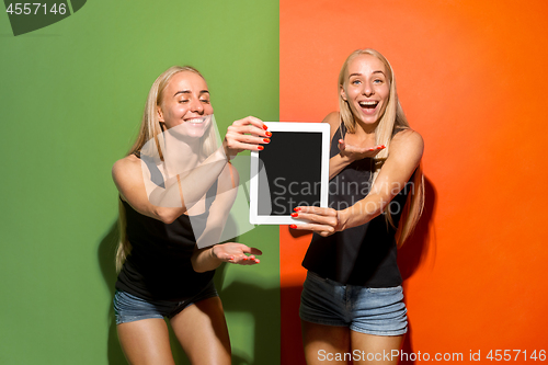 Image of Portrait of a confident casual girls showing blank screen of laptop isolated over colorful background