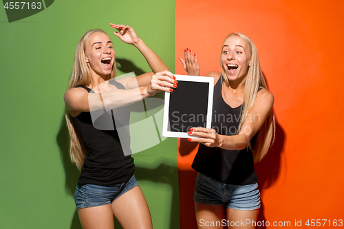 Image of Portrait of a confident casual girls showing blank screen of laptop isolated over colorful background