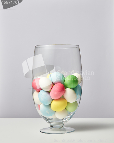 Image of Glass vase with lots of small painted eggs on a gray background with copy space. Easter card layout