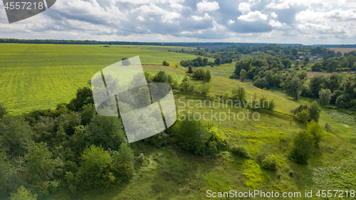 Image of Summer rural landscape with green fields, meadows, forests against cloudy background. Aerial view from drone.