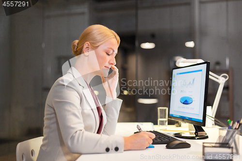 Image of businesswoman calling on sartphone at night office