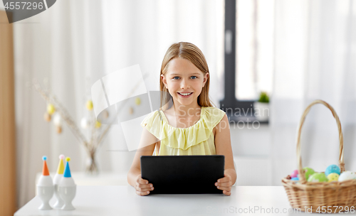 Image of happy girl with tablet pc and easter eggs at home