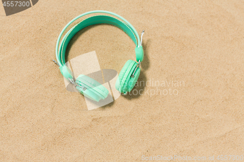 Image of earphones on summer beach sand