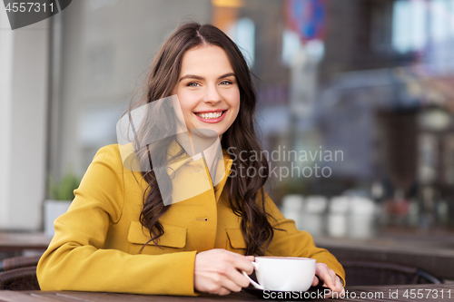 Image of teenage girl drinking hot chocolate at city cafe