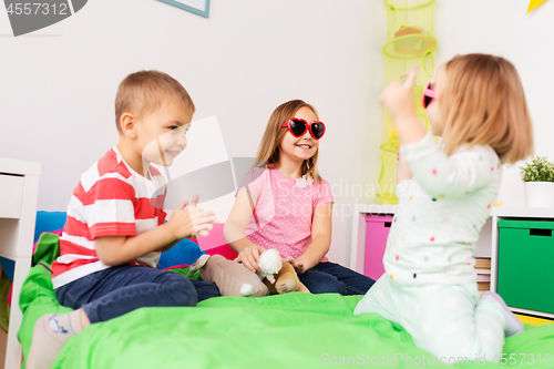 Image of happy little kids in sunglasses playing at home