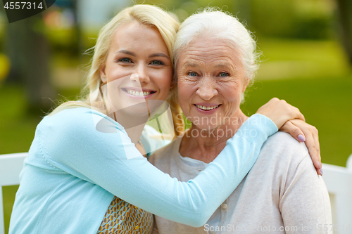 Image of daughter with senior mother hugging on park bench